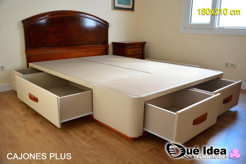Ejemplo montado de cama de 180x210 cm con cajones abiertos modelo Plus tapizado en polipiel color crudo con tiradores y zócalo de madera color cerezo, montada en Sevilla a juego con cabecero y mesitas