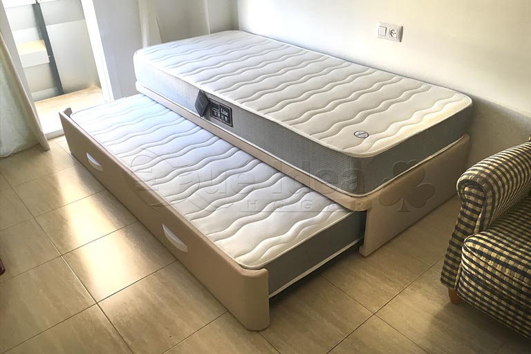 Cama individual nidotapizada en polipiel color beige con dos colchones incluidos en la oferta